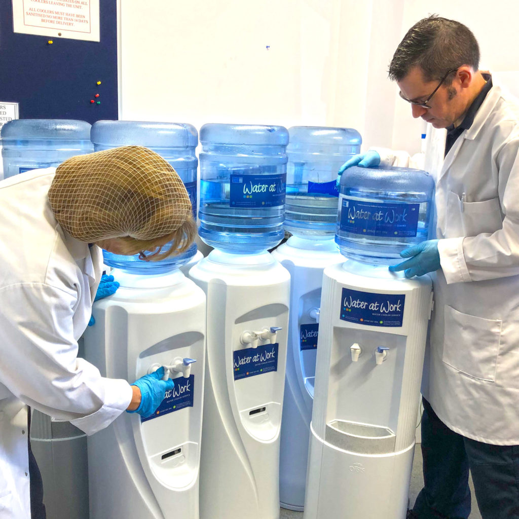 Employees sanitising water coolers.